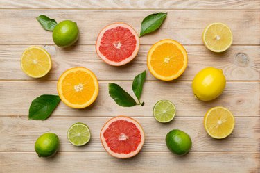 Citrus fruits such as lime, orange and lemon with lemon tree leaves on light-colored background