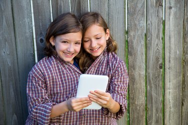 twin girls dressed up pretending be siamese and tablet pc