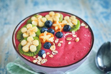 Pitaya smoothie in bowl with kiwi, banana, blueberries and superfoods on top