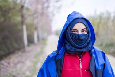 Front view of a woman wearing a ski mask while standing outdoors and looking camera