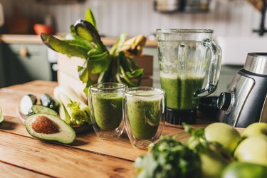 healthy green smoothie with banana, spinach, avocado and chia seeds in a glass bottles on a rustic background