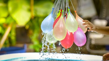 Cropped Child Hand Reaching Towards Water Bombs