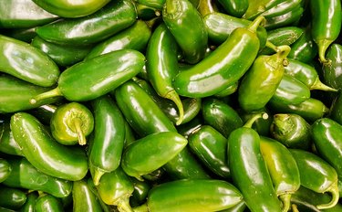 Raw green Jalapeno peppers on a supermarket display.