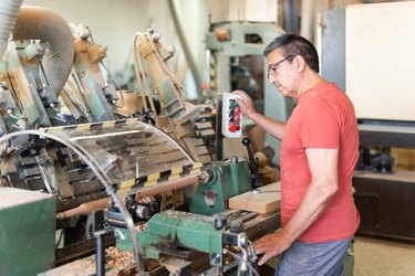 Man working turning a wooden baluster. Manufacturing process.