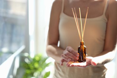 Woman holding diffuser with wooden sticks for aroma oil