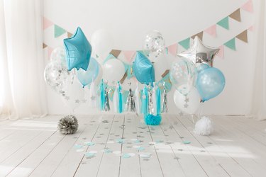 Festive background decoration for birthday celebration with gourmet cake and blue balloons in studio, cake smash first year concept