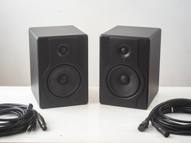 Black Pro Studio Speakers with Cables against a White and Gray Surface