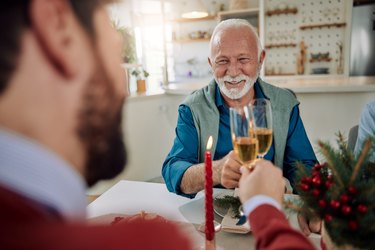 A smiling older man and his son celebrating Christmas together and toasting with champagne