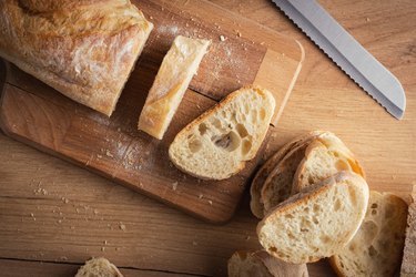 Whole-grain bread on wood cutting board on wood kitchen table