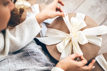 Close-up of a woman wrapping gifts and tying a beautiful pastel ribbon bow