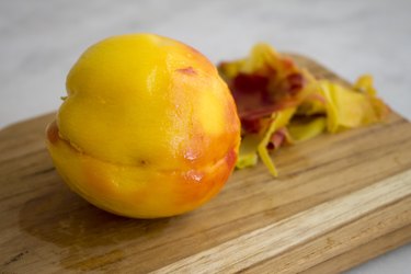 Peeled peach on a wood cutting board