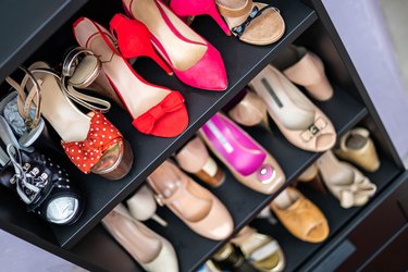 Gray closet shelves full of fashion female shoes on heels pair storage organization of cupboard