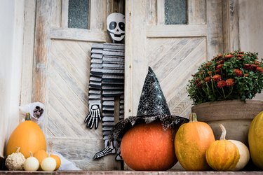 Halloween-decorated front door with various sizes and shapes of pumpkins and a skeleton