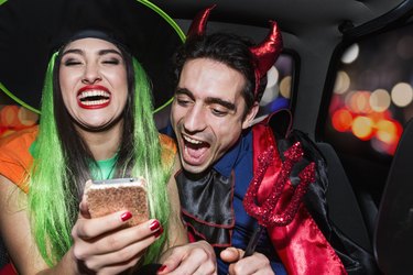 Halloween witch and devil laughing in back of car