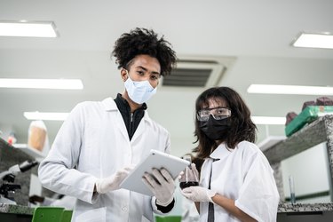 Portrait of students doing an experiment and using digital tablet in the lab