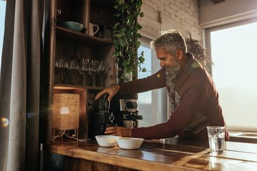 Senior man making espresso at home.