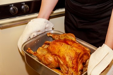 Woman holds a baked crispy turkey for Thanksgiving