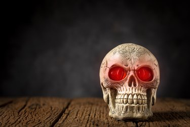 Halloween catrine skull on an old wooden table in black background.