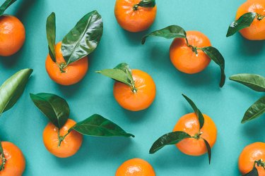 Fresh mandarins with leaves on turquoise background