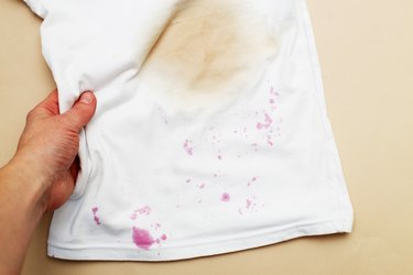 dirty stains on a white T-shirt from berries and drink on brown background