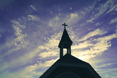 heavenly religious church chapel steeple in silhouette against a azure blue purple cloudscape sky