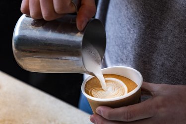 Man hands holding fresh coffee or latte art in a cup at coffee shop and restaurant, bar or pub