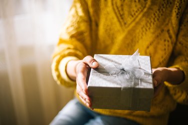 Young woman in yellow sweater holding gift box