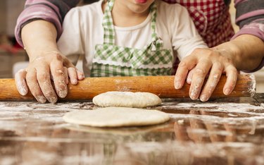 Grandma and granddaughter stretching dough