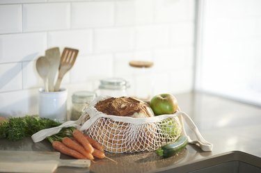 Fresh bread, organic vegetables and fruit on a plastic free zero waste kitchen worktop.