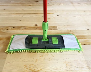 Cleaning wooden floor with mop, laminate floor top view.