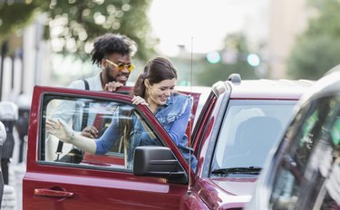 Multi-ethnic young adults in city, getting in parked car