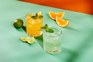 Multi-colored cocktails in glasses of different shapes on colored backgrounds with hard shadows