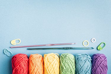 Crochet composition with cotton rainbow yarn, crochet hooks and accessories. Flat lay overhead shot with copy space, toned photo