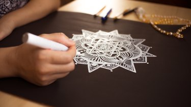 Drawing Mandala On Black Paper At Table