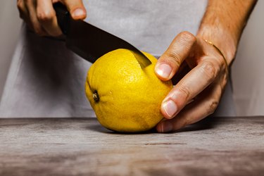 Male hands cutting a ripe lemon with a knife