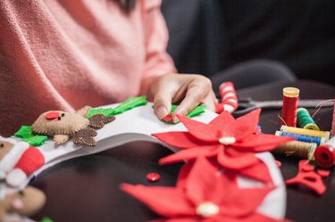 Woman stitching holly berry onto christmas decoration, mid section