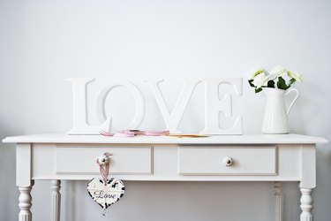 Love decorations, ribbon, roses and card on desk