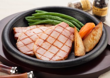 A plate of grilled ham steak with beans