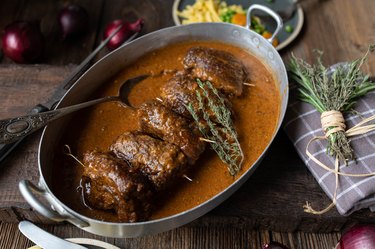 German beef roulades in a rustic roasting pan on wooden table