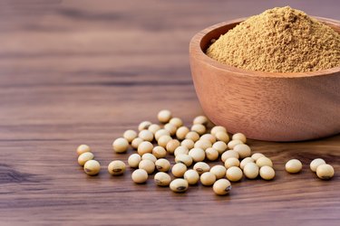 Soybean and soy bean protein powder in wooden bowl isolated on wooden table background