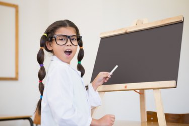 Cute pupil dressed up as scientist in classroom