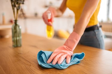 Woman wiping the dining table surface with cloth