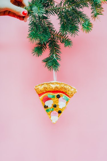 Artificial pizza slice decor hanging on Christmas tree spruce branch