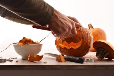 Detail of man carving a pumpkin for the halloween party