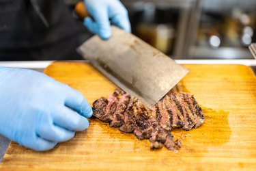 Chef slicing roast beef using cleaver knife