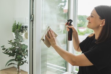 Scrubwoman cleaning a window using eco-friendly cleaning products.