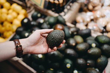 Choosing an avocado at grocery store