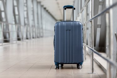 Closeup Shot Of Stylish Cabin Baggage Suitcase Standing In Empty Airport Hall