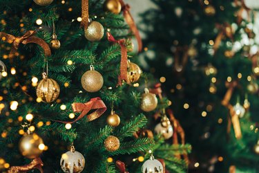 Green artificial tree is hung with baubles and garland