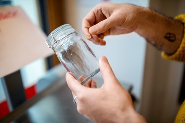 Hands of male customer labeling glass jar at zero waste store